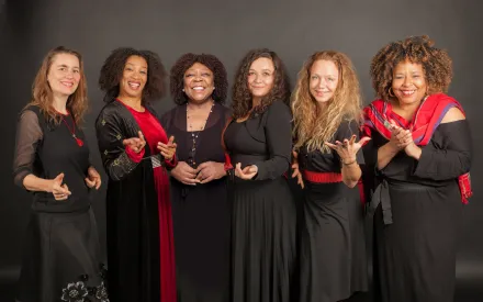Sechs Frauen in schwarz rot gekleidet, nebeneinander in einer Reihe stehend