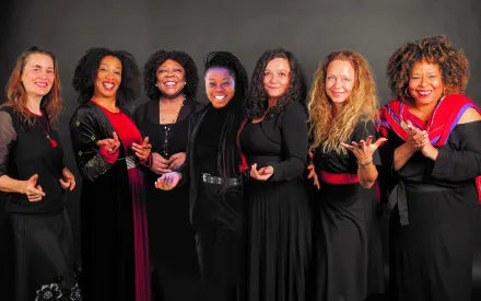 Sieben Frauen in schwarz rot gekleidet, nebeneinander in einer Reihe stehend