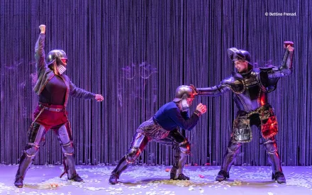 Drei Frauen in Ritterinnenkostümen vor einem Kettenvorhang, kämpfend