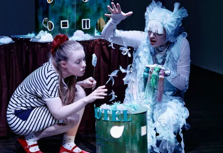 Zwei Performerinnen bewundern in einer fantasievoll anmutenden Kulisse fliegende kleine Wesen