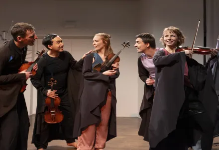 Fünf Musiker*innen mit Streichinstrumenten musizieren gemeinsam auf der Bühne.