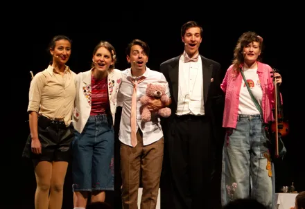 Fünf Darsteller*innen stehen gemeinsam auf der Bühne und strahlen in einer fröhlichen Abschlussgeste.