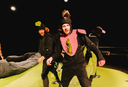 Schauspieler in fantasievollen schwarzen Kostümen auf der Bühne.