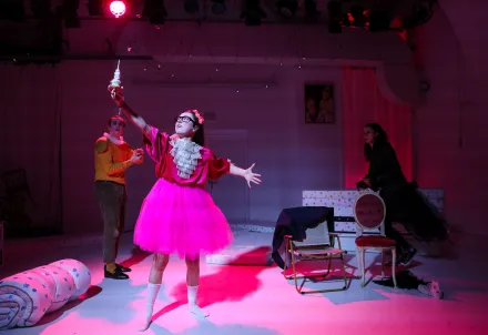 eine prinzessin in pinkem tüll gekleidet präsentiert mit ausladender geste eine Spindel