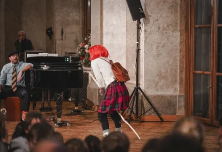 You said: short descripotion like this;   Person in weißem Anzug kniet und zielt mit einem langen Stock auf eine Reihe roter und schwarzer Kugeln auf glänzendem Boden     ChatGPT said:  Person in weißem Kostüm mit Netzstoff und grünen Bällen hebt einen grünen Ring in die Luft und schaut mit offenem Mund nach oben, vor schwarzem Hintergrund. You said: ChatGPT said:  Zwei Personen in hellen Kostümen stehen auf der Bühne; eine hält einen Strauß roter Stäbe und reicht der anderen einen einzelnen roten Stab vor schwarzem Hintergrund. You said: ChatGPT said:  Zwei Personen in einer dunklen Szene: Eine leuchtet mit einer Taschenlampe auf die andere, die erschrocken an einer Backsteinwand steht. You said: ChatGPT said:  Zwei Personen stehen an Keyboards auf der Bühne, umgeben von bunten Neonlinien im Hintergrund, und zeigen mit erhobenen Schlägeln spielerisch aufeinander. You said: ChatGPT said:  Zwei Personen stehen vor bunten Neonlinien an Keyboards und Mikrofonen; sie performen mit energiegeladener Gestik und musikalischem Ausdruck auf der Bühne. You said: ChatGPT said:  Person mit weißem Haar, weißer Bluse und rotem Rock steht lächelnd mit ausgebreiteten Armen im Park vor einem Baum und einem Wandteppich mit Einhornmotiv. You said: Der_kleine_Diktator_2_(c)Die_Kurbel ChatGPT said:  Person in gestreiftem Sakko hält eine übergroße schwarze Schachfigur in der Hand und blickt mit theatralischem Ausdruck darauf, vor schwarzem Hintergrund. You said: ChatGPT said:  Mehrere Personen in hellen Kostümen agieren auf einer Bühne mit grünen und roten Kugeln; im Hintergrund stehen Musikinstrumente und Mikrofone, das Licht reflektiert auf dem glänzenden Boden. You said: ChatGPT said:  Drei Personen in hellen Kostümen agieren auf einer dunklen Bühne mit grünen und roten Kugeln; im Hintergrund stehen Schlagzeug und Mikrofone. You said: COPYRIGHT SYMBOL ChatGPT said:  Here you go: ©  You can copy it directly — it’s the standard copyright symbol. You said: ChatGPT said:  Drei Personen auf einer dunklen Bühne, umgeben von leuchtend grünen und roten Kugeln; eine spielt Violine, während die anderen zwischen Instrumenten und Lichteffekten agieren. You said: description  for  each ChatGPT said:  1️⃣ Erstes Bild: Eine Gruppe junger Darsteller*innen sitzt in einer Reihe auf einem Stuhl, mit ausdrucksstarken Gesichtern und erhobenen Armen, während hinter ihnen eine Projektion von furchterregenden Drachen zu sehen ist.  2️⃣ Zweites Bild: Ein Darsteller sitzt entspannt in einem Sessel, während im Hintergrund eine Figur mit übergroßem Kopf auf einem Sofa liegt; auf der Leinwand dahinter wirbeln blaue, abstrakte Formen.  3️⃣ Drittes Bild: Mehrere junge Darsteller*innen toben auf der Bühne mit Kissen, während eine Figur mit weißem Bart und Dreizack auf einem Sofa steht – im Hintergrund leuchtet eine blaue Projektion wie eine Explosion oder ein Auge. You said: is there a short cut for this symbol on the keyboard © ChatGPT said:  Yes! Here are the shortcuts depending on your device:  💻 Windows:      Hold Alt and type 0169 on the numeric keypad → ©     (Make sure Num Lock is on.)  ⌨️ Mac:      Press Option + G → ©  🖥️ Linux:      Press Ctrl + Shift + U, then type 00A9, then press Enter → ©  📱 Phone/Tablet:      On-screen keyboard → long-press the C key → select ©  Would you like me to show how to make it appear automatically in Word or Canva too? You said: its a german keyboard ChatGPT said:  Got it 👍 — on a German keyboard, here’s how you can type ©:  💻 Windows (German layout):      Hold Alt and type 0169 on the number pad → ©     (Num Lock must be on.)  ⌨️ Mac (German layout):      Press ⌥ Option + G → ©  🖋️ Alternative (works anywhere):      Copy & paste: ©  Would you like me to tell you how to set up a quick text shortcut (so typing “(c)” automatically becomes © in Word or Canva)? You said: 232  ChatGPT said:  Eine Frau mit goldener Krone und Umhang steht strahlend im Bühnenlicht, während hinter ihr Darsteller*innen in gebückter Haltung und bunte Zeltelemente vor einer blauen Projektion zu sehen sind. You said: ChatGPT said:  Person hält zwei ausdrucksstarke Handpuppen mit grotesken Gesichtern vor rotem, feurig wirkendem Hintergrund – eine lebendige Theaterszene voller Farbe und Kontrast. You said: ChatGPT said:  Person steht hinter einer bunt bemalten Stoffkulisse mit Meeresmotiven und Fischen im Vordergrund sowie einer grünen, pflanzenverzierten Landschaft im Hintergrund. You said: description for each ChatGPT said:  1️⃣ Erstes Bild: Eine Darstellerin in einem Kleid aus recyceltem Material hebt entschlossen die Faust, während im Hintergrund ein grünes Graffiti mit dem Schriftzug „WAKE UP“ erscheint.  2️⃣ Zweites Bild: Zwei Tänzer*innen in bunten Kostümen aus Plastik und Stoff bewegen sich dynamisch unter einer Projektion der Erde – eine Szene voller Energie und Bewegung.  3️⃣ Drittes Bild: Zwei Performer*innen stehen auf der Bühne mit ausgebreiteten Armen, über ihnen schwebt ein Bild der Erde – ein Moment zwischen Hoffnung und Nachdenklichkeit.  4️⃣ Viertes Bild: Zwei Darsteller*innen in farbenfrohen, plastikartigen Kostümen umarmen sich expressiv vor einer Projektion mit globalen Temperaturdaten – ein starkes Bild zum Klimawandel. You said: ChatGPT said:  Zwei Performer*innen in bunten, aus Recyclingmaterial gefertigten Kostümen stehen mit ausgebreiteten Armen auf einer hellen Bühne, während im Hintergrund ein Bild der Erde über einer blauen Projektionsfläche schwebt. You said: ChatGPT said:  Zwei Performer*innen in bunten Kostümen aus recyceltem Material stehen in einer intensiven Pose vor einer Projektion mit globalen Temperaturdaten – ein eindringliches Bild zum Thema Klimawandel. You said: ChatGPT said:  Zwei Performer*innen in farbenfrohen Kostümen aus recycelten Materialien stehen barfuß auf der Bühne und blicken auf eine riesige Projektion der Erde – ein symbolischer Moment über Verantwortung und Zukunft des Planeten. You said: kurzer ChatGPT said:  Zwei Performer*innen in bunten Recyclingkostümen blicken auf eine große Projektion der Erde. You said: Zwei Performer*innen in bunten Kostümen aus recyceltem Material stehen in einer intensiven Pose vor einer Projektion mit globalen Temperaturdaten – ein eindringliches Bild zum Thema Klimawandel. ChatGPT said:  Zwei Performer*innen in bunten Recyclingkostümen posieren vor einer Projektion globaler Temperaturdaten – ein starkes Bild zum Klimawandel. You said: Zwei Performer*innen in bunten, aus Recyclingmaterial gefertigten Kostümen stehen mit ausgebreiteten Armen auf einer hellen Bühne, während im Hintergrund ein Bild der Erde über einer blauen Projektionsfläche schwebt. ChatGPT said:  Zwei Performer*innen in bunten Recyclingkostümen stehen mit ausgebreiteten Armen vor einer Projektion der Erde. You said: ChatGPT said:  Eine Darstellerin in einem Kleid aus Recyclingmaterial hebt kämpferisch die Faust, vor einer Projektion mit dem Schriftzug „WAKE UP“. You said: ChatGPT said:  Person betrachtet eine fantasievolle Miniaturbühne vor einer groß projizierten, farbintensiven Unterwasser- oder Traumwelt-Szene. You said: ChatGPT said:  Eine Performerin interagiert auf der Bühne mit einer groß projizierten Unterwasserwelt voller bunter, lächelnder Meeresfiguren. You said: ChatGPT said:  Eine Person filmt eine fantasievolle Miniaturkulisse in Blautönen, während im Hintergrund eine vergrößerte Meeresfigur projiziert wird. You said: ChatGPT said:  Detailaufnahme einer fantasievollen Unterwasserfigur mit Tentakeln aus Stoffbändern und einem großen Auge, in eine blaue Bühnenkulisse eingebettet. You said: ChatGPT said:  Drei Performer*innen kriechen neugierig unter einem grauen Vorhang hervor – eine verspielte Szene, die Neugier und Entdeckergeist ausdrückt. You said: thank u make them as short and clear as possible ChatGPT said:  Of course! Here are the shortened and clear versions of all your image descriptions so far:      c_Barbara Palffy (5).jpg     Zwei Performer*innen in bunten Recyclingkostümen in einer intensiven Pose vor Temperaturdaten.      c_Barbara Palffy (9).jpg     Zwei Performer*innen in Recyclingkostümen stehen mit ausgebreiteten Armen vor einer Erdkugel-Projektion.      c_Barbara Palffy (6).jpg     Performer*in in Recyclingkostüm ruft zum Handeln auf – Projektion „WAKE UP“ im Hintergrund.      1920_©ReinhardWinkler_druck.jpg     Person filmt eine Miniaturkulisse, dahinter eine vergrößerte Meeresprojektion.      1920 2_©ReinhardWinkler_druck.jpg     Bühnenbild mit Meeresszene und Projektion bunter Unterwasserfiguren.      1920 3©hydro_Kulturverein_druck.JPG     Detail einer Unterwasserfigur mit Tentakeln und großem Auge in blauer Kulisse.      _DSC5119 (c) Laurent Ziegler, Bildrecht.jpg     Drei Performer*innen kriechen neugierig unter einem Vorhang hervor.  Would you like me to format them for a press kit or image credit list (e.g. add © and titles)? You said: ChatGPT said:  Drei Performer*innen kriechen neugierig unter einem Vorhang hervor. You said: very veryy good thank you ChatGPT said:  You’re so welcome 😊 I’m glad you liked it! Would you like me to make all your other image descriptions match this short, clean style (one concise line each)? You said: ChatGPT said:  Drei Performer*innen mit Sonnenbrillen musizieren und singen voller Energie. You said: ChatGPT said:  Ein Musiker hängt kopfüber an einer Stange und spielt Geige. You said: ChatGPT said:  Zwei Performer*innen tanzen mit weit ausgebreiteten schwarzen Umhängen. You said: ChatGPT said:  Fünf Musiker*innen mit Streichinstrumenten musizieren gemeinsam auf der Bühne. You said: ChatGPT said:  Drei Performer*innen kriechen neugierig unter einem grauen Vorhang hervor. You said: c fopright ChatGPT said:  © Laurent Ziegler, Bildrecht You said: ChatGPT said:  Vier Darsteller*innen in einer farbenfrohen Theaterszene – Musik, Emotion und Humor vereinen sich auf der Bühne. © Sara Schober You said: ChatGPT said:  Eine humorvolle Theaterszene in einem eleganten Restaurant – Musik, Chaos und Charme vereinen sich. © Sara Schober You said: ChatGPT said:  Eine lebendige Bühnenszene mit Musik und Schauspiel – Humor trifft auf klassische Eleganz. © Sara Schober You said: ChatGPT said:  Fünf Darsteller*innen stehen gemeinsam auf der Bühne und strahlen in einer fröhlichen Abschlussgeste. © Sara Schober You said: ChatGPT said:  Eine dynamische Theaterszene voller Bewegung und Humor – im Mittelpunkt ein rosa Teddybär auf einem goldenen Stuhl. © Sara Schober You said: i want to change the size of most images to 1920 by 1080 without losng quality for the website ChatGPT said:  Perfect — that’s a great idea for your website! Here’s exactly how you can resize your images to 1920×1080 pixels without losing quality, depending on which tools you’re comfortable with 👇 🖥️ Option 1: Canva (Free & Easiest)      Open Canva      .      Click Create a design → Custom size → 1920 × 1080 px.      Upload your image.      Right-click the image → “Set image as background” (so it fills without cropping).      Adjust position slightly if needed.      Click Download → File type: JPG or PNG → Quality: 100%.  ✅ Tip: Use PNG for sharper images (like theater stills) and JPG for faster website loading. 💻 Option 2: Photoshop or Photopea (Free alternative)      Go to photopea.com      .      Open your image → Image → Image Size → Set width = 1920 px, height = 1080 px.          Make sure “Resample: Preserve Details (enlargement)” is selected.      Export → File → Export As → JPG or PNG → Quality 100%.  ✅ This method gives you the most control over quality. 🧠 Option 3: Batch resize (if you have many files)  If you have many theater photos:      Use IrfanView, XnConvert, or Lightroom → Batch resize all to 1920×1080.      Keep DPI around 300 if they’re also for print, or 72 for web-only.  Would you like me to help you batch-convert the images you uploaded into 1920×1080 automatically and send them back ready for your website? If yes, I can resize them for you here and preserve sharpness. You said: ooption 2 which is hohe and ChatGPT said:  Perfect — you’re choosing Option 2: Photopea, which is actually the best free “Photoshop-style” online tool for high-quality (hohe Qualität) resizing. Here’s your quick step-by-step guide in English + German so you can follow easily 👇 🧑🏽‍💻 Option 2 – Photopea (Free & High-Quality) 🔗 Go to: https://www.photopea.com 🇬🇧 Steps in English      Open your image          Click File → Open and choose your photo.      Resize it          Go to Image → Image Size          Type Width: 1920 px, Height: 1080 px          Make sure the checkbox Resample is ON          From the dropdown, choose Preserve Details (enlargement)      Export / Save          Go to File → Export As → JPG or PNG          Set Quality: 100 %          Click Save  ✅ Your image will now be exactly 1920 × 1080 px and still sharp. 🇩🇪 Schritte auf Deutsch      Bild öffnen          Klicke auf Datei → Öffnen und wähle dein Foto aus.      Größe ändern          Gehe zu Bild → Bildgröße          Gib Breite: 1920 px, Höhe: 1080 px ein          Stelle sicher, dass Neu berechnen aktiviert ist          Wähle im Dropdown Details erhalten (Vergrößerung)      Exportieren / Speichern          Datei → Exportieren als → JPG oder PNG          Qualität: 100 %          Speichern klicken  ✅ Dein Bild hat jetzt genau 1920 × 1080 Pixel und bleibt in hoher Qualität.  Would you like me to give you a preset template for Photopea (so you just drag & drop each image, and it automatically exports in 1920×1080 px, 100 % quality)? You said: ChatGPT said:  Nahaufnahme von Händen, die mit Ton und bunten Objekten arbeiten – ein kreativer Moment voller Struktur und Farbe. © Bettine Frenzel You said: ChatGPT said:  Eine Musikerin in pinkem Hemd spielt konzentriert auf einer Handpan – ein Moment stiller Klangkunst. © Bettine Frenzel You said: ChatGPT said:  Kinder gestalten gemeinsam eine bunte Landschaft aus Ton und Spielobjekten – kreatives Chaos voller Fantasie. © Bettine Frenzel You said: ChatGPT said:  Ein Kind drückt seine Hand in eine strukturierte Tonfläche – sinnliches Erleben und kreatives Entdecken. © Bettine Frenzel You said: ChatGPT said:  Mehrere erhobene, tonverschmierte Hände – ein Moment gemeinsamer Kreativität und Ausdruck. © Bettine Frenzel You said: ChatGPT said:  Eine Performerin in rotem Overall bewegt sich über den Boden, bedeckt mit weißen Handabdrücken aus Ton. © Bettine Frenzel You said: ChatGPT said:  Eine Performerin formt konzentriert einen großen Tonklumpen – Kreativität in Bewegung. © Bettine Frenzel You said: ChatGPT said:  Zwei Performerinnen im Dialog, verbunden durch Gesten und Ton – ein Moment voller Achtsamkeit. © Bettine Frenzel You said: ChatGPT said:  Kinderhände ertasten Ton und Struktur – ein sinnliches Spiel mit Material und Form. © Bettine Frenzel You said: ChatGPT said:  Ein Clown voller Energie und Witz – direkt, frech und herzlich. © Jan Zaslawski You said: ChatGPT said:  Ein Clown in Bewegung – verspielt, lebendig und voller Ausdruck. © Jan Zaslawski You said: ChatGPT said:  Ein Clown im Moment – voller Gefühl, Humor und Poesie. © Jan Zaslawski You said: ChatGPT said:  Ein Clown zwischen Ernst und Komik – überrascht, neugierig und charmant. © Jan Zaslawski You said: ChatGPT said:  Stark, geheimnisvoll und furchtlos – ein moderner Kriegerblick. © Apollonia T. Bitzan You said: ChatGPT said:  Ein Spiel aus Licht, Schatten und Bewegung – poetisch und geheimnisvoll. © Bettina Frenzel You said: ChatGPT said:  Kraftvoll, verspielt und kämpferisch – ein moderner Rittermoment auf der Bühne. © Bettina Frenzel You said: ChatGPT said:  Stille nach dem Kampf – Rüstung abgelegt, Emotion bleibt. © Bettina Frenzel You said: ChatGPT said:  Stärke und Nachdenklichkeit im Schein der Rüstung – ein Moment innerer Spannung. © Bettina Frenzel You said: ChatGPT said:  Kreatives Spiel mit Schwerkraft und Balance – Theater voller Leichtigkeit. © Samirezaei You said: ChatGPT said:  Lebendige Geschichten mit einem Lächeln erzählt – voller Fantasie und Herz. © Barbara Pálffy You said: ChatGPT said:  Ein Moment voller Staunen – wenn Geschichten lebendig werden. © Barbara Pálffy You said: ChatGPT said:  Lebendige Geschichten voller Fantasie und Lebensfreude. © Barbara Pálffy You said: ChatGPT said:  Magische Momente zwischen Fantasie und Erzählkunst. © Barbara Pálffy You said: Alternativtext (Suchmaschienen und Barrierefreiheit) ChatGPT said:  Hier ist ein passender Alternativtext (Alt-Text) für Suchmaschinen und Barrierefreiheit für dieses Bild:  Deutsch: Ein Mann mit rotem Turban und weißem Hemd liest in einem großen, roten Buch in einer dschungelartigen Umgebung. Das Licht betont sein erstauntes Gesicht, während Pflanzen den Hintergrund füllen.  Englisch (für zweisprachige Websites): A man wearing a red turban and white shirt reads a large red book in a jungle-like setting. His surprised expression is highlighted by the warm light, surrounded by lush greenery.  Möchtest du, dass ich Alt-Texte auch für die anderen beiden Bilder (z. B. das lachende Porträt und das mit den Tierfiguren) erstelle, damit sie konsistent für die Website optimiert sind? You said: short ChatGPT said:  Deutsch: Mann mit rotem Turban liest ein rotes Buch im Dschungel. Englisch: Man with red turban reading a red book in the jungle. You said: ChatGPT said:  Deutsch: Mann mit rotem Turban hält ein Buch mit Tierfiguren und Pflanzen. Englisch: Man with red turban holding a book with animal figures and plants. You said: ChatGPT said:  Deutsch: Schauspielerin spielt mit einer großen grünen Handpuppe auf der Bühne. Englisch: Actress performing with a large green puppet on stage. You said: two different ChatGPT said:  Natürlich — hier sind zwei verschiedene Alternativtexte für die beiden Bilder:  📸 Erstes Bild: Deutsch: Schauspielerin hält eine große grüne Handpuppe vor sich, während sie auf der Bühne steht. Englisch: Actress holds a large green puppet in front of her while performing on stage.  📸 Zweites Bild: Deutsch: Schauspielerin lacht und bewegt eine grüne Puppe auf der Bühne vor dunklem Vorhang. Englisch: Actress smiles and moves a green puppet on stage in front of a dark curtain. You said: c ChatGPT said:  1. © Susanne Preissl 2. © Susanne Preissl You said: ChatGPT said:  1. © Alexander Dirninger 2. © Alexander Dirninger You said: Alternativtext (Suchmaschienen und Barrierefreiheit) ChatGPT said:  Hier sind zwei kurze Alternativtexte für Suchmaschinen und Barrierefreiheit:  📸 Erstes Bild: Deutsch: Zwei Schauspieler auf einer Bühne mit blauer Stofflandschaft, einer steht im Vordergrund, der andere spielt Gitarre im Hintergrund. Englisch: Two actors on stage with a blue fabric landscape; one stands in front, the other plays guitar in the background.  📸 Zweites Bild: Deutsch: Schauspieler steht mit Zitronen in den Händen vor einer blauen Bühnenlandschaft, Musiker sitzt dahinter. Englisch: Actor holds lemons on stage in front of a blue fabric set, with a musician sitting behind him. You said: short ChatGPT said:  1. Schauspieler vor blauer Stofflandschaft, Musiker im Hintergrund. 2. Schauspieler mit Zitronen, Musiker im Hintergrund. You said: has to be a real sentence ChatGPT said:  1. Zwei Schauspieler stehen auf einer Bühne mit blauer Stofflandschaft. 2. Ein Schauspieler hält Zitronen, während ein Musiker im Hintergrund sitzt. You said: ChatGPT said:  Eine Tänzerin springt mit gestreckten Beinen über einen weißen Stuhl auf der Bühne. You said: ChatGPT said:  Eine Tänzerin bewegt bunte, wehende Stoffbahnen in leuchtenden Farben auf der Bühne. You said: ChatGPT said:  Eine Tänzerin steht auf der Bühne, während ein blauer Stoff von einem Ventilator in die Luft geweht wird. You said: ChatGPT said:  Eine Tänzerin kniet auf der Bühne und hält ein wehendes blaues Tuch über einem Ventilator. You said: ChatGPT said:  Zwei Darsteller in schwarzen Kostümen umarmen sich auf der Bühne, einer trägt eine Mütze mit einem grünen Blatt darauf. You said: c ChatGPT said:  Zwei Schauspieler in schwarzen Kostümen umarmen sich, einer trägt eine Mütze mit einem grünen Blatt. You said: okay moving forward i need short and clear and copyright ChatGPT said:  Got it 👍 — short, clear, and ending with copyright format like: „© [Fotografname]“  Example:      Eine Tänzerin mit blauem Tuch auf der Bühne. © Jelmer de Haas  Would you like me to follow this exact style for all upcoming ones? You said: ChatGPT said:  Zwei Schauspieler in schwarzen Kostümen umarmen sich auf der Bühne. © You said: ChatGPT said:  Drei Tänzer formen gemeinsam eine bunte, akrobatische Pose. © Meinrad Hofer You said: ChatGPT said:  Schauspieler in fantasievollen schwarzen Kostümen auf der Bühne. © Apollonia Theresa Bitzan You said: ChatGPT said:  Vier Schauspieler in schwarzen Kostümen stehen dicht beieinander auf der Bühne. © Apollonia Theresa Bitzan You said: ChatGPT said:  Drei Musikerinnen mit Schreibmaschine, Saxophon und Geige vor blauem Hintergrund. © Maria Frodl You said: ChatGPT said:  Zwei Künstlerinnen mit goldenen Accessoires und bemalten Gesichtern posieren vor blauem Hintergrund. © Töchter der Kunst You said: ChatGPT said:  Vier Musikerinnen mit verschiedenen Instrumenten vor hellblauem Hintergrund. © Maria Frodl You said: ChatGPT said:  Ein Künstler in rotem Hemd steht vor einem roten Vorhang und spricht auf der Bühne. © Erika Mayer You said: ChatGPT said:  Ein Mann in roter Samtjacke steht lächelnd im Freien. © Tobias Garcia-Navas You said: ChatGPT said:  Ein Musikerensemble spielt auf einer Bühne mit rotem Vorhang vor einem applaudierenden Publikum. © Erika Mayer You said: ChatGPT said:  Mehrere LEGO-Figuren stehen auf bunten Bauplatten in einer Dschungelumgebung. © Olympus Kids You said: ChatGPT said:  Eine Frau steht lächelnd an einem Tisch mit Miniaturlandschaft und Laptop, während im Hintergrund ein großes Foto projiziert wird. © Franzi Kreis You said: ChatGPT said:  Eine Frau arbeitet an einem beleuchteten Tisch mit LEGO-Figuren und Pflanzenmodellen, während eine Projektion im Hintergrund zu sehen ist. © Franzi Kreis You said: ChatGPT said:  Eine Frau arbeitet konzentriert an einem LEGO-Modell unter hellem Licht, neben ihr steht ein Laptop. © Franzi Kreis You said: ChatGPT said:  Eine Frau präsentiert auf der Bühne eine LEGO-Szene, die groß im Hintergrund projiziert wird. © Franzi Kreis You said: ChatGPT said:  Eine Maulwurf-Figur mit orangefarbener Lampe und gestreiftem Shirt steht zwischen grünen Pflanzen. © Scarlett Köfner You said: ChatGPT said:  Eine detailreiche Insektenfigur mit Geige und Zylinder sitzt am Hafen vor Segelbooten. © Micha Pöllmann You said: ChatGPT said:  Eine Maulwurf-Figur in gestreiftem Shirt lehnt an einer Säule in einem sonnigen Innenhof. © Micha Pöllmann You said: ChatGPT said:  Eine Insektenfigur mit Hut und Geige liegt entspannt im grünen Blattwerk. © Scarlett Köfner You said: ChatGPT said:  Vier Schauspieler:innen stehen in einer intensiven Theaterszene auf der Bühne. © Theresa Pewal You said: ChatGPT said:  Eine Schauspielerin sitzt auf einer Leiter, hält eine Papierrolle und blickt nachdenklich in den Raum. © Theresa Pewal You said: ChatGPT said:  Vier Darsteller:innen interagieren lebhaft auf der Bühne, eine Person springt in die Luft. © Theresa Pewal You said: ChatGPT said:  Eine bunte Puppe mit gestreifter Hose und gelbem Halstuch steht an einer Steinmauer. © Scarlett Köfner You said: ChatGPT said:  Drei Künstler:innen liegen farbenfroh auf dem Boden, umgeben von Instrumenten und Stoffen. © Julia Wesely You said: ChatGPT said:  Vier Darsteller:innen in bunten Outfits performen energiegeladen auf blauer Matte. © Bettina Frenzel You said: ChatGPT said:  Vier Darsteller:innen drängen sich um ein Mikrofon und singen gemeinsam. © Bettina Frenzel You said: ChatGPT said:  Zwei Personen erzeugen mit Licht und Objekten poetische Schattenspiele. © Michael Watzenig You said: ChatGPT said:  Zwei Künstler arbeiten konzentriert mit Licht und Miniaturfiguren an einem Tisch. © Michael Watzenig You said: ChatGPT said:  Zwei Performer knien auf dem Boden und bewegen kleine Figuren in einer beleuchteten Szene. © Michael Watzenig You said: ChatGPT said:  Zwei Personen feiern lachend, während bunte Blätter durch die Luft wirbeln. © Sara Schober You said: ChatGPT said:  Zwei Performer in bunten Kostümen musizieren und spielen lebhaft auf der Bühne. © Sara Schober You said: ChatGPT said:  Eine Darstellerin mit roter Perücke und Schulrucksack steht auf der Bühne vor einem Publikum, während ein Musiker am Klavier sitzt.