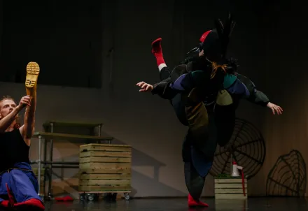 Tänzer*innen in einer dynamischen Bewegungsszene – ein farbenfrohes Kostüm trifft auf präzise Körperspannung.