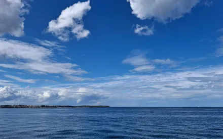 gewässer mit leichten wellen und gekräuselter Wasseroberfläche, blauer Himmer mit Wolken